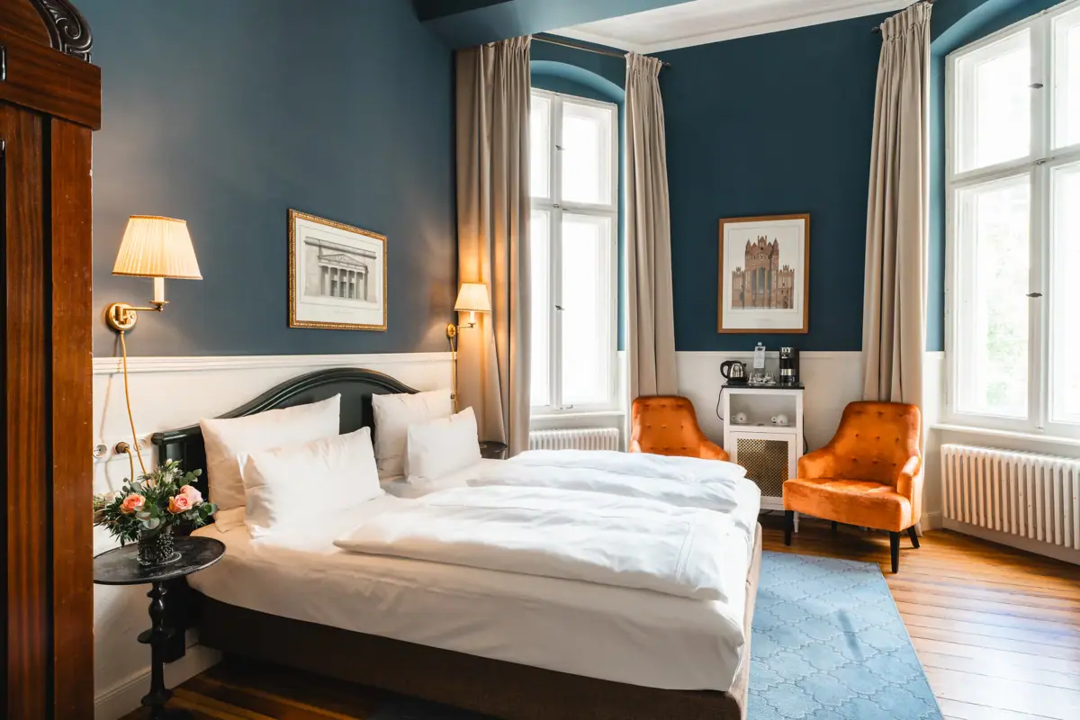 A room at the HENRI Hotel Berlin with two beds and chairs.