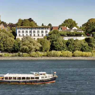 A small barge floats on the Elbe in front of the Louis C. Jacob Hotel in Hamburg.