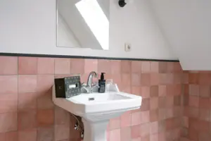 A washbasin with a mirror hanging above it in the bathroom.
