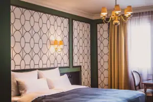 A bed with elegant bedding and a chandelier, framed by luxurious curtains.