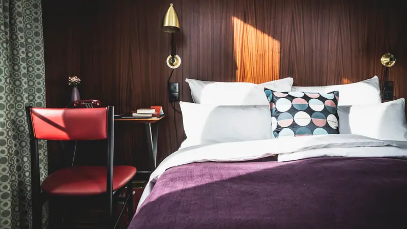Bed with pillows and a desk in front of it in the hotel room.