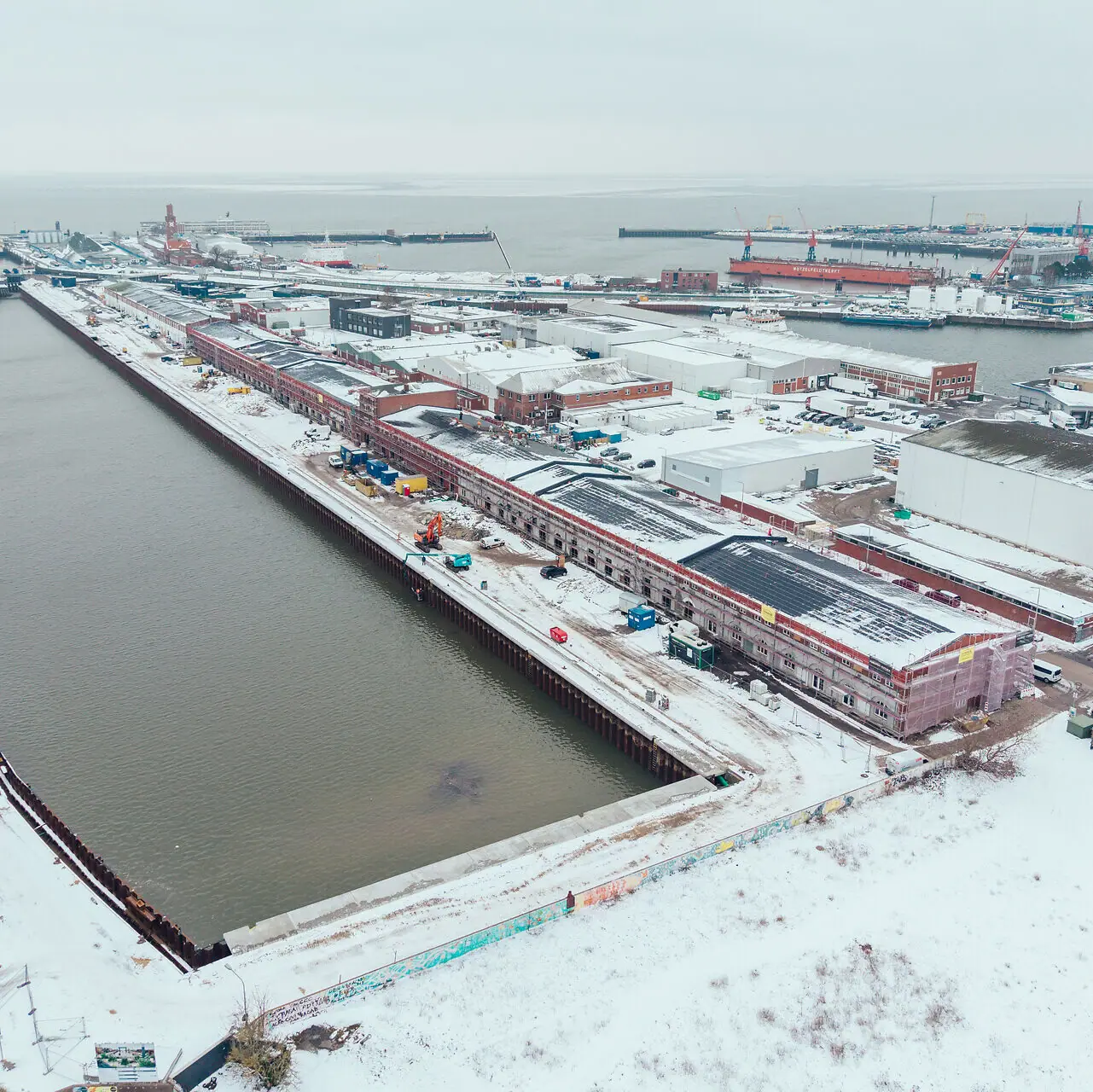 A bird's eye view of a snow-covered town next to a body of water in winter.