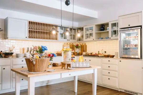 A kitchen with white cupboards and a table with flowers.