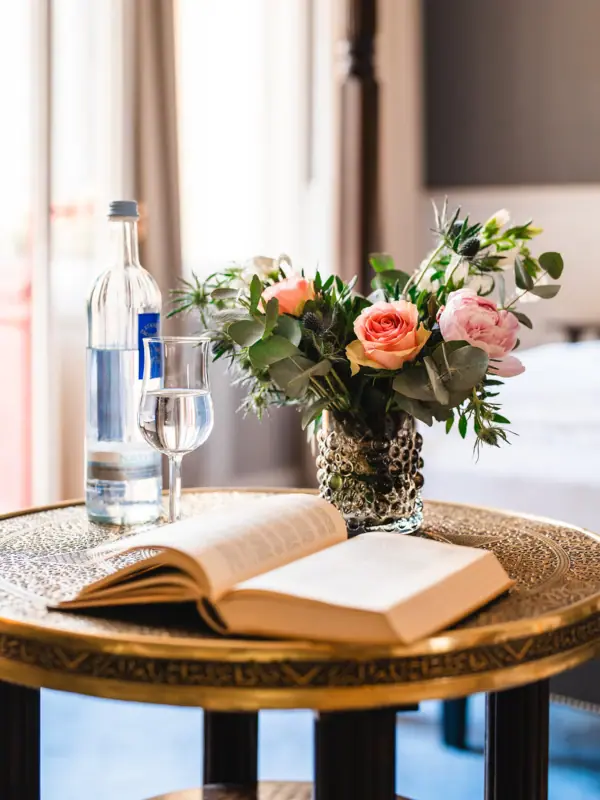A book and a vase of flowers on a table.