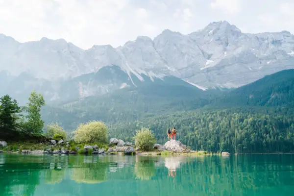 People standing on a rock in front of a lake.