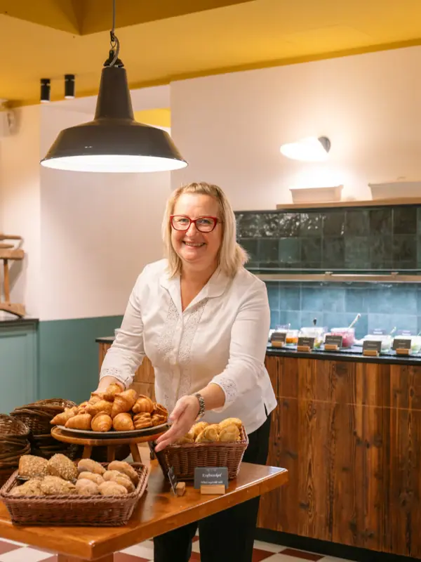 A woman smiling while holding a tray of snacks indoors.
