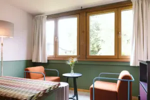 A seating area with two armchairs in front of a window in the Chambre hotel room at the HENRI Hotel Garmisch-Partenkirchen.