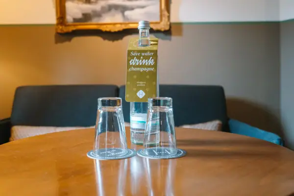 A bottle and glasses on a table in a hotel room at the HENRI Hotel in Garmisch-Partenkirchen.