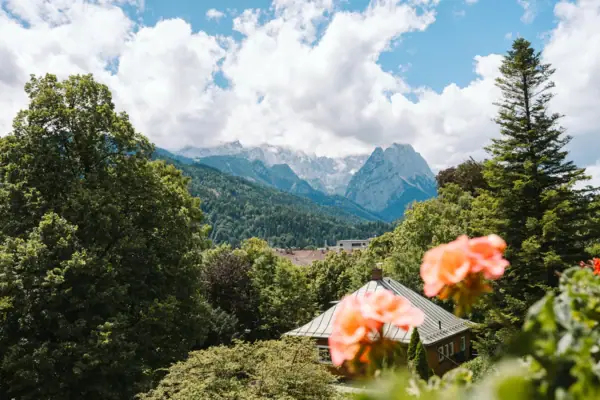 View from the balcony of the HENRI Hotel Garmisch-Partenkirchen with flowers and mountains in the background.