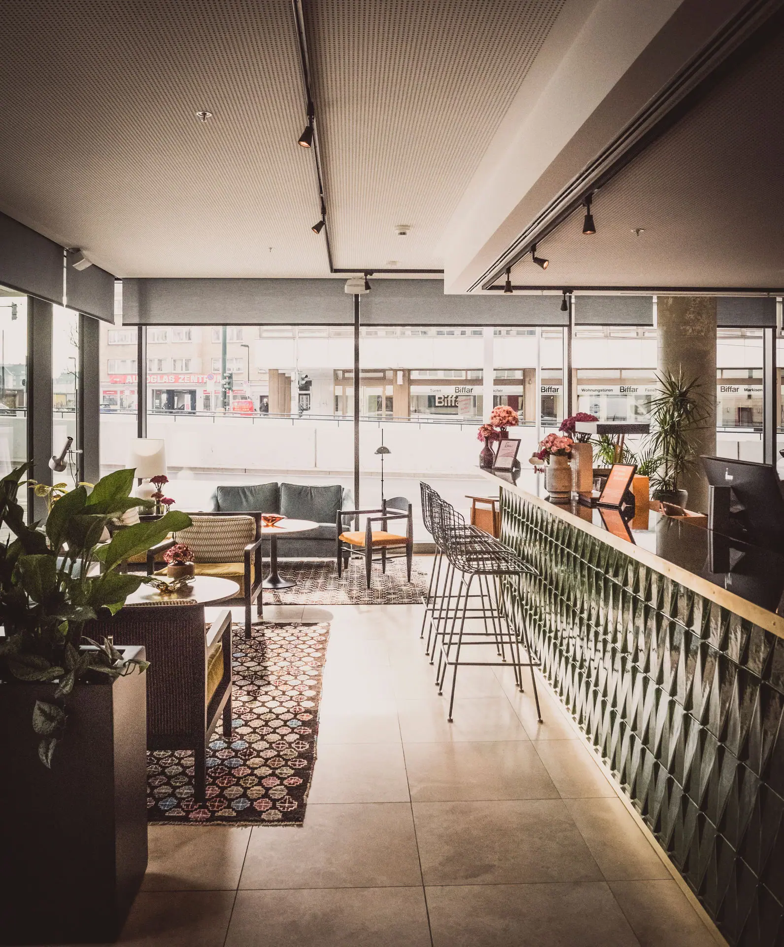 A room with a bar and chairs, featuring furniture and houseplants.