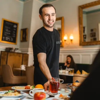 A man smiles at a table with food.