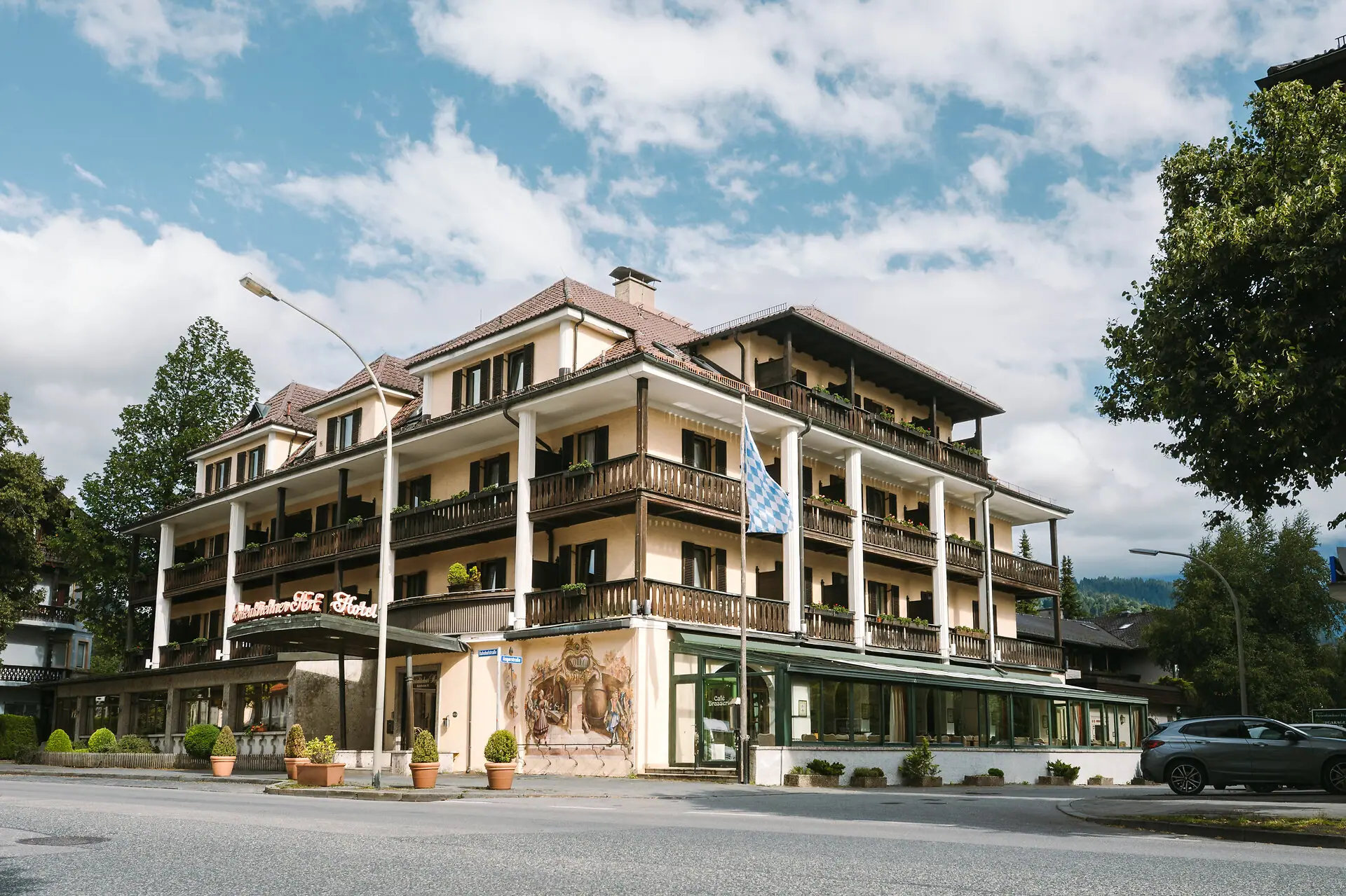 Exterior view of the HENRI Hotel in Garmisch-Partenkirchen, with trees and a road.