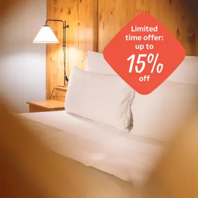 A bed with white pillows and a lampshade.