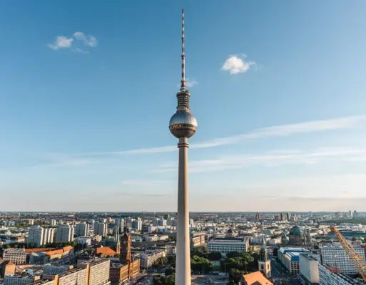 Berlin television tower with large pointed structure in the centre in front of a cloudy sky.