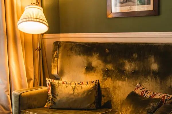 A sofa with cushions and a lamp in a room.