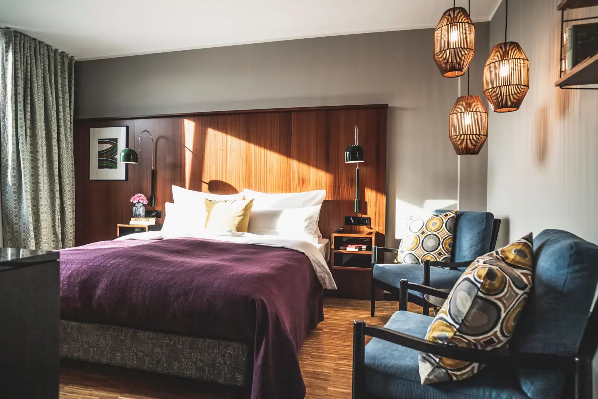 A hotel room with a bed and chairs.