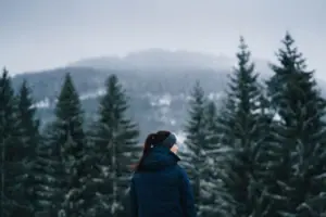 Kitzbühel Alps A woman is standing outdoors in front of snow-covered trees.