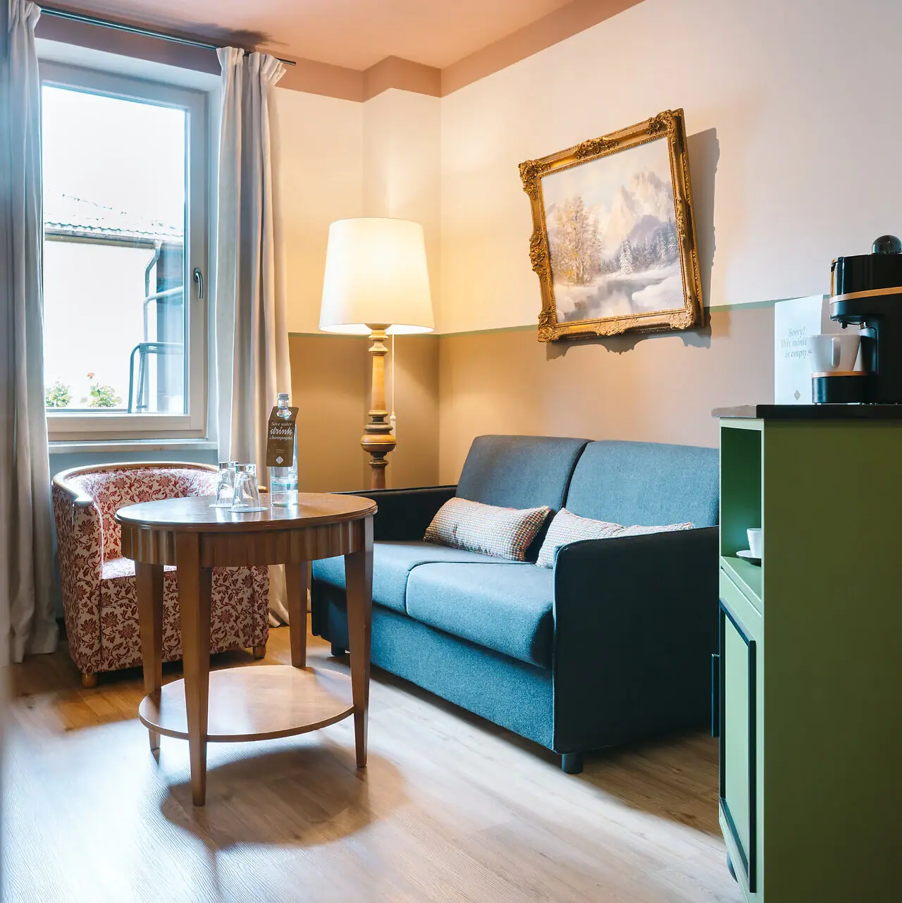 Living area in a hotel room at the HENRI Garmisch-Partenkirchen with a sofa and a table.