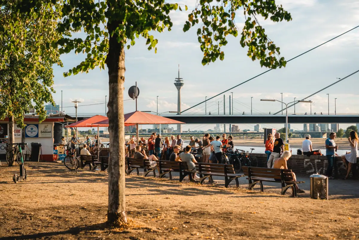 A group of people are sitting on benches in a park.