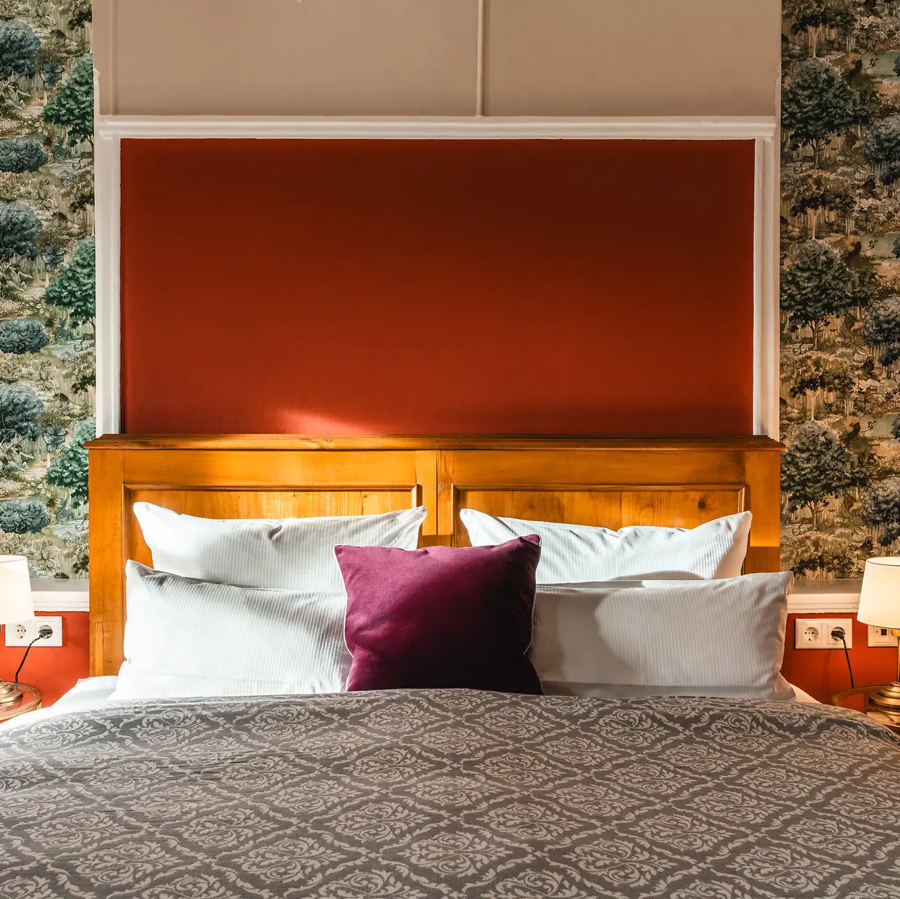 A bed with a red and white cushion.