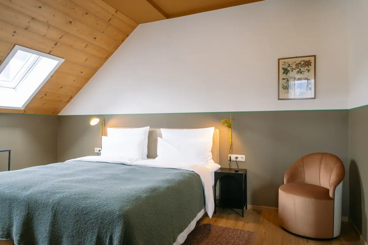 A bed in a stylishly furnished room, complete with pillows and bed linen.