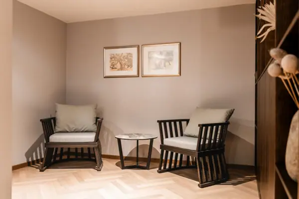 A room with chairs and a table, furnished with a sofa, wooden floor and a coffee table.