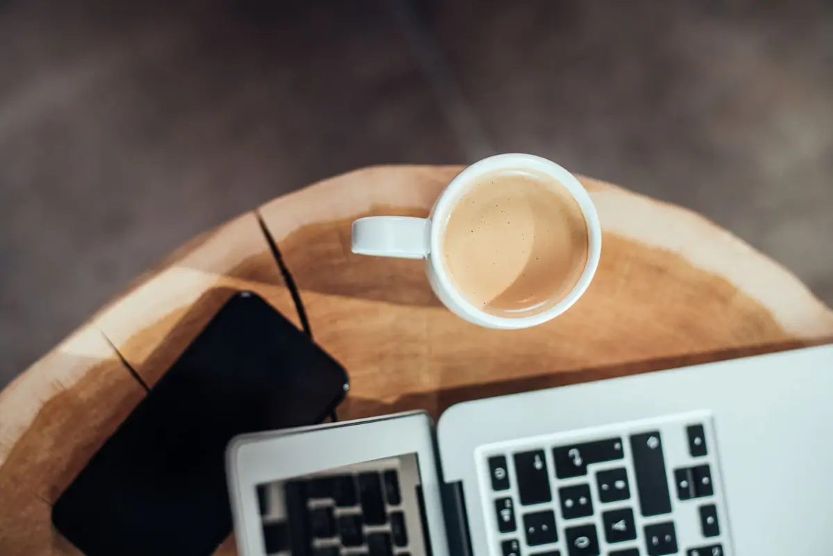 A cup of coffee and a laptop on a table.