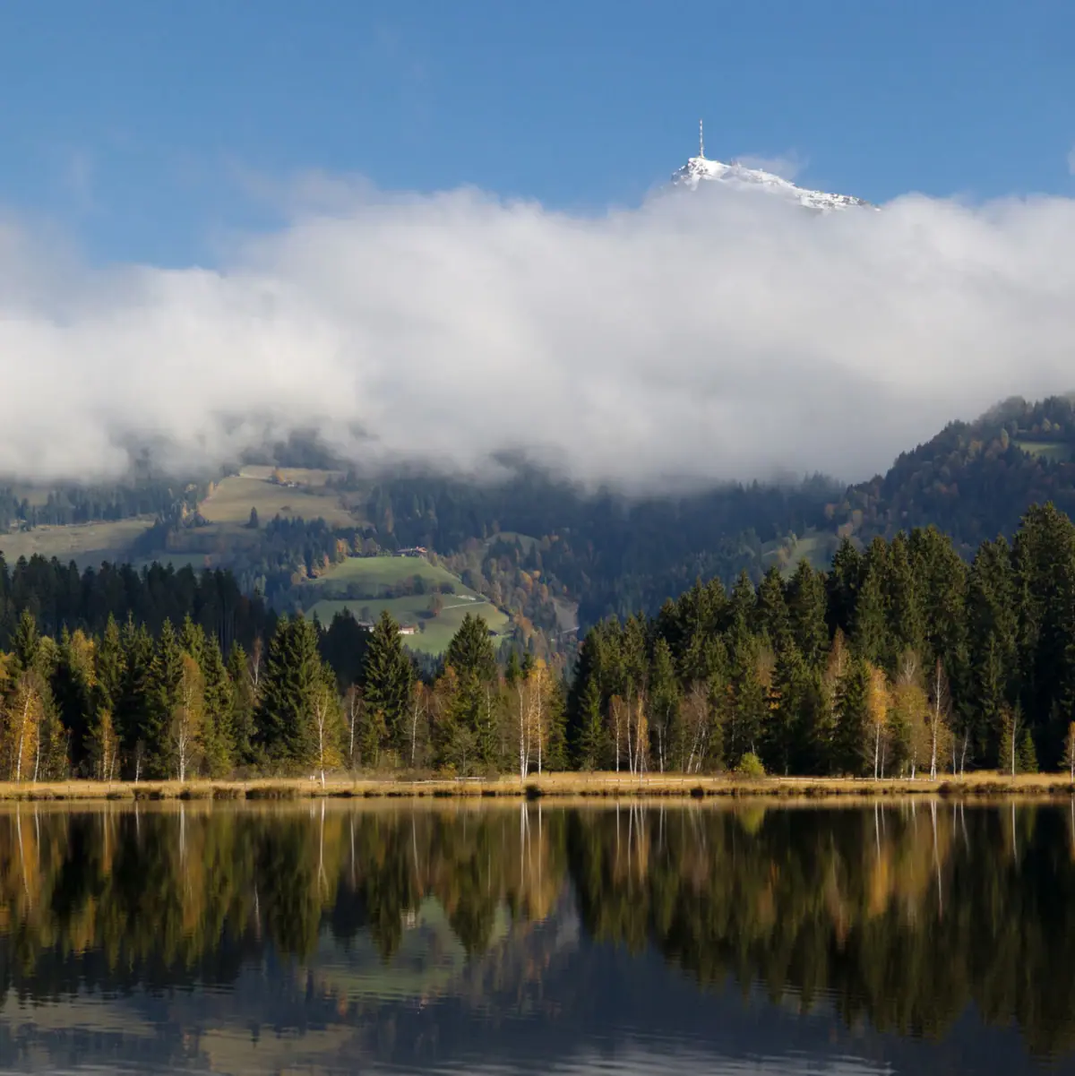 Kitzbühel Schwarzsee A lake with trees and mountains in the background.