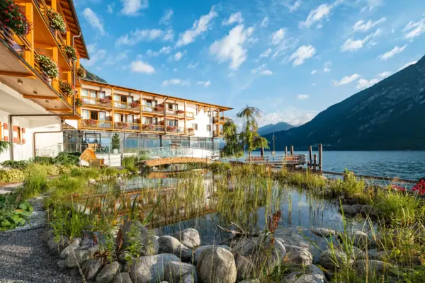 the aja Fürstenhaus on Lake Achensee with a pond and mountains in the background.