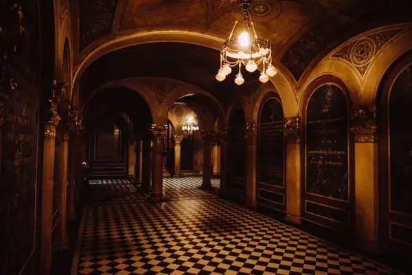 A hallway with columns and chandeliers.