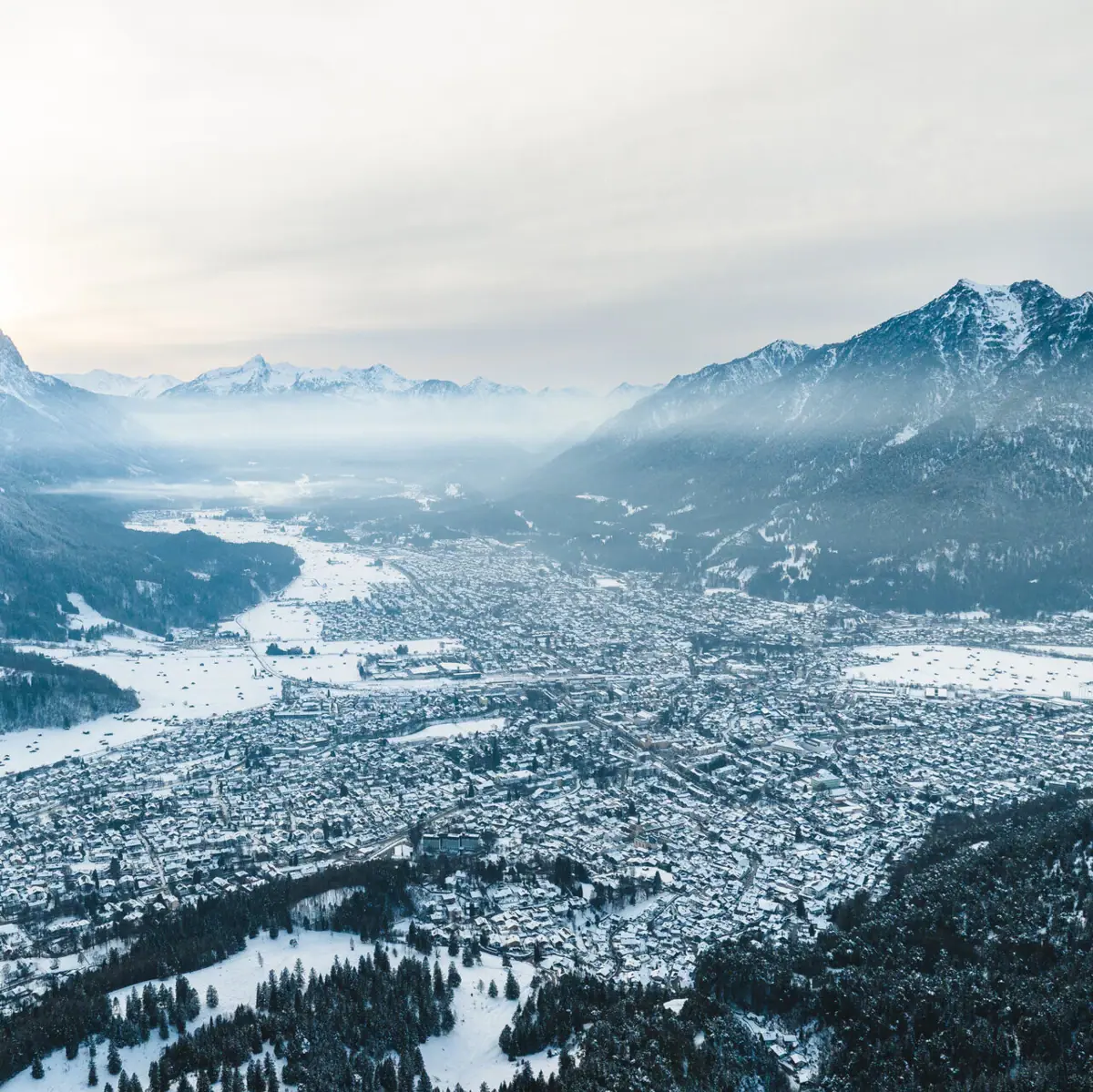 A snow-covered city with mountains in the background.