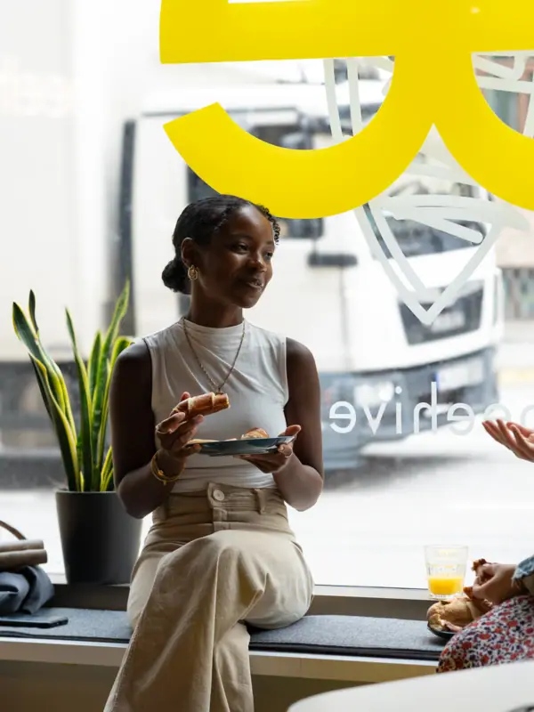 A woman sits on a windowsill and eats.