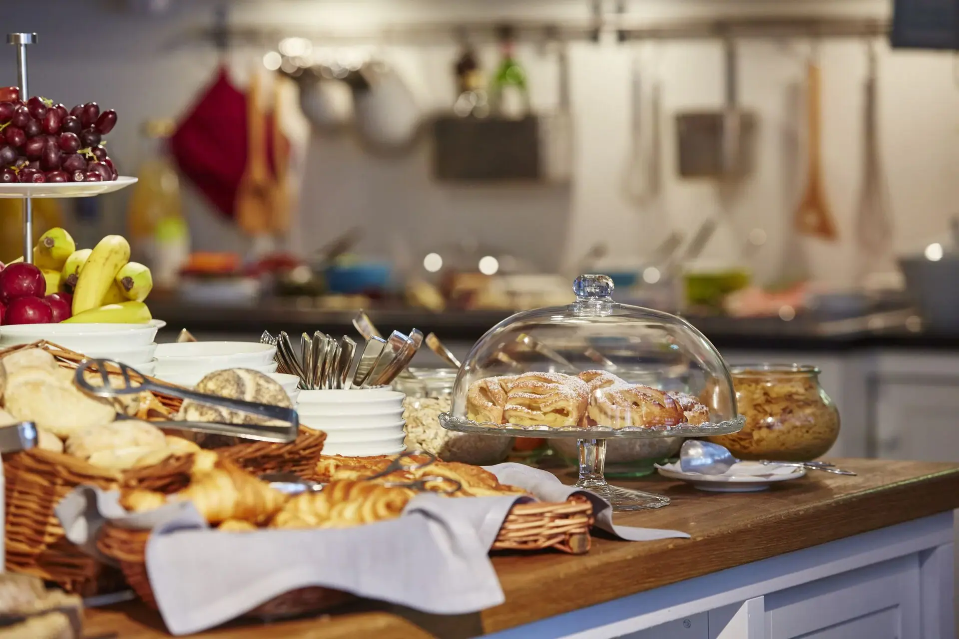 Kitchen island with bread rolls, croissants and fruit.