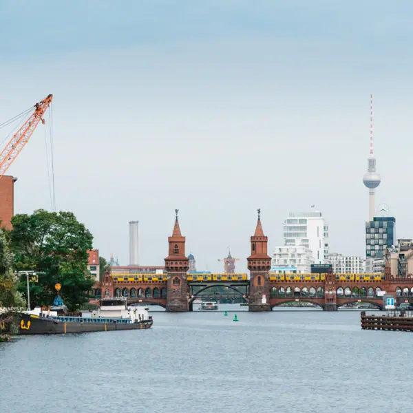 A bridge over a river with a crane and a town in the background.