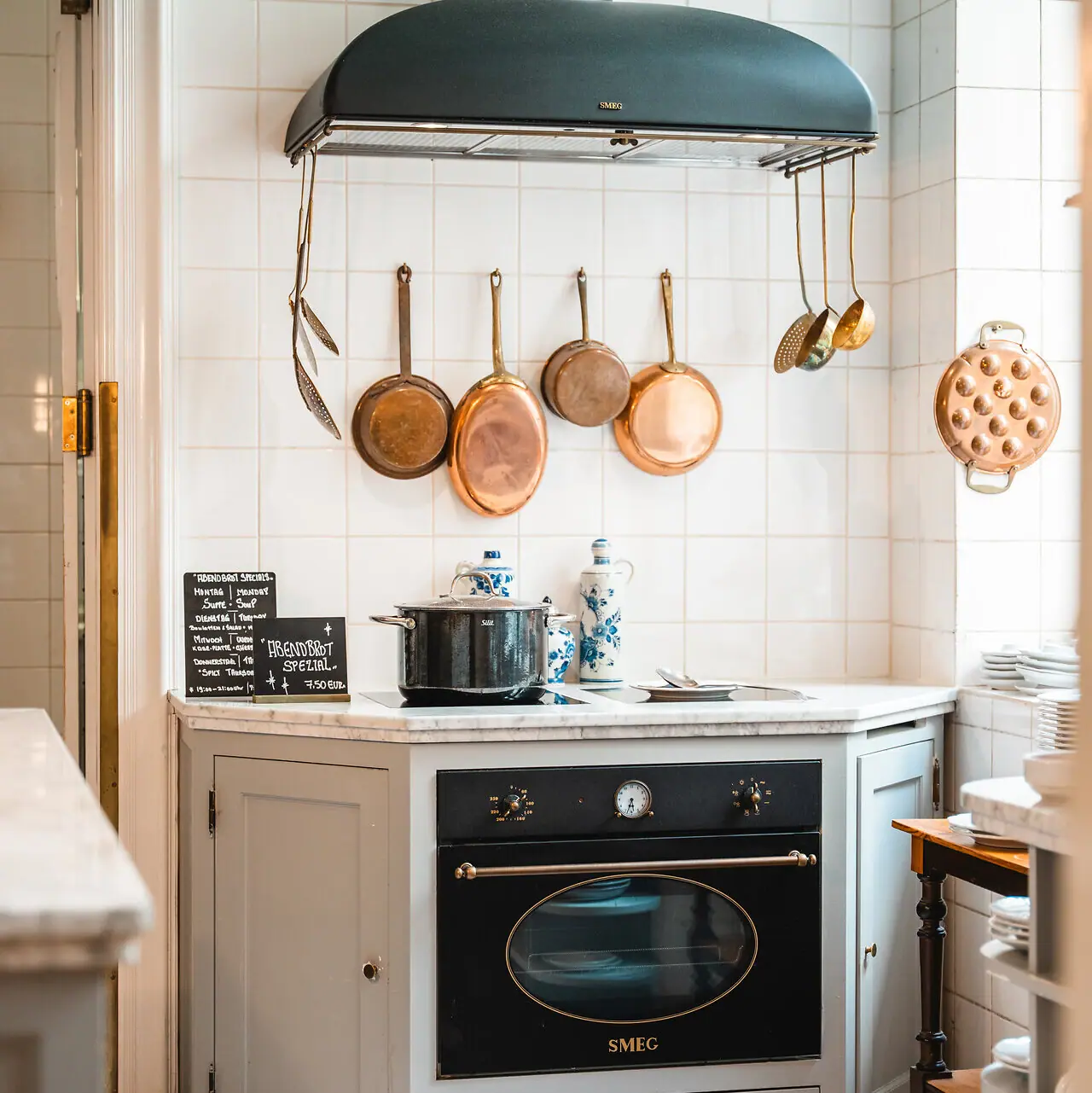 A kitchen with a cooker and pots on the wall.