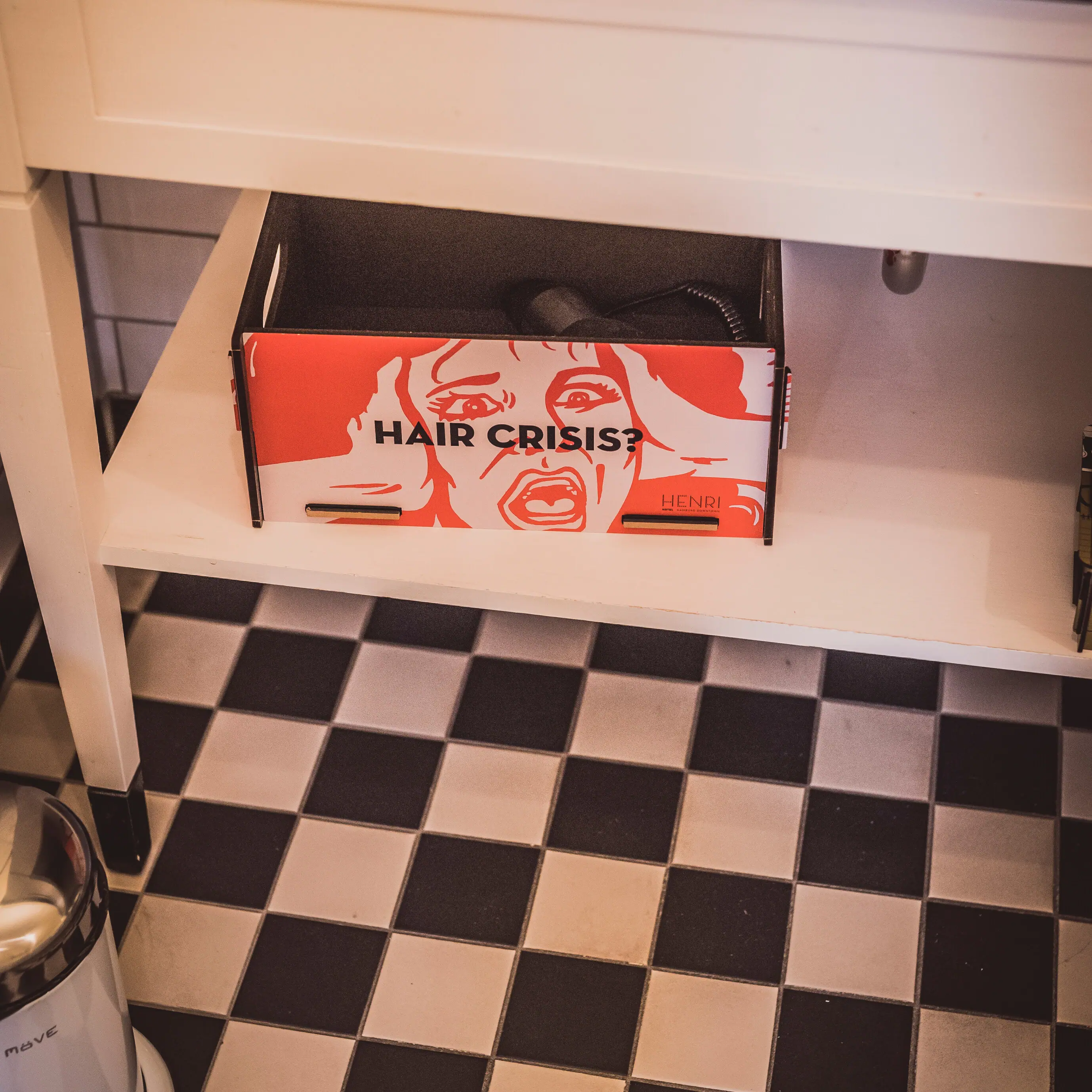 Colourful box with hairdryer on a bathroom shelf