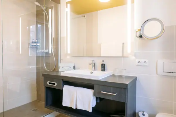 Bathroom at the HENRI Hotel Garmisch-Partenkirchen, featuring a glass shower cubicle and a washbasin