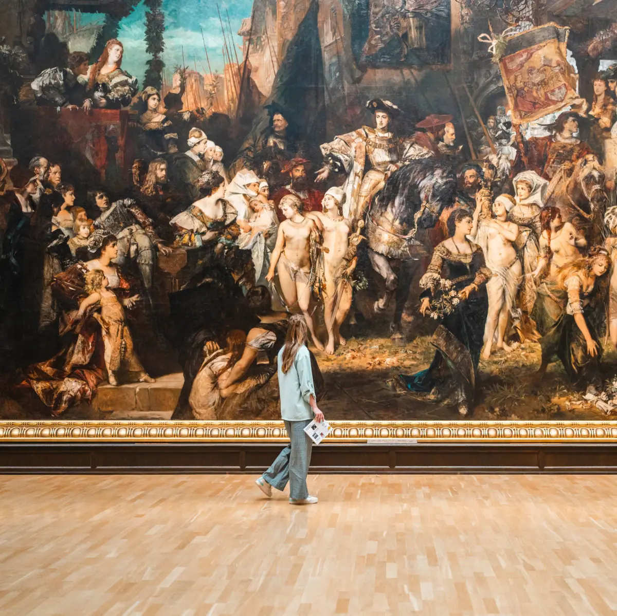 A woman walks in front of a large painting.