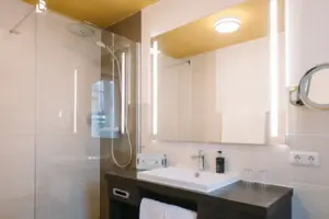A bathroom with washbasin and mirror at the HENRI Hotel Garmisch-Partenkirchen.