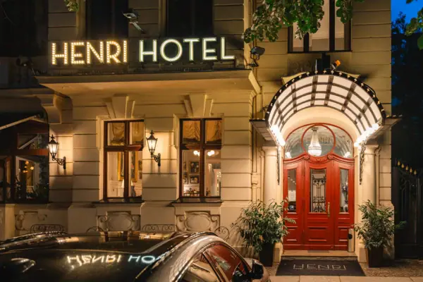 Die beleuchtete Fassade und der Eingangsbereich des HENRI Hotels Berlin in einem historischen Gründerzeithaus bei Nacht.