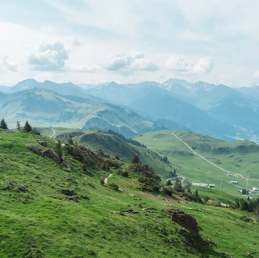 Green hills with a road and mountains in the background.