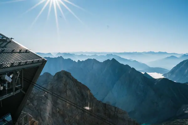 The view from the Zugspitze with mountain range, cable car and bright sunshine.