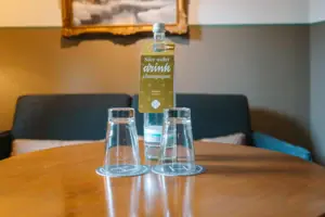 A bottle and glasses on a table in a hotel room at the HENRI Hotel in Garmisch-Partenkirchen.