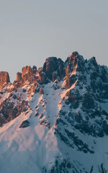 Snow-covered mountains behind a village with houses and trees.