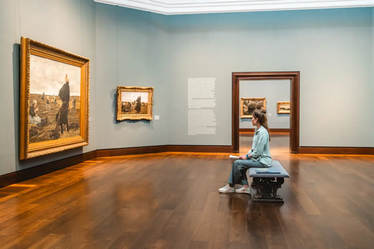 A woman sits on a bench in a museum.