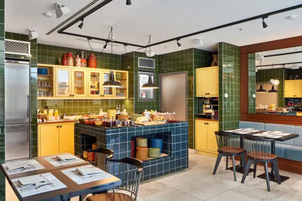 A room with green tiles and yellow cupboards.