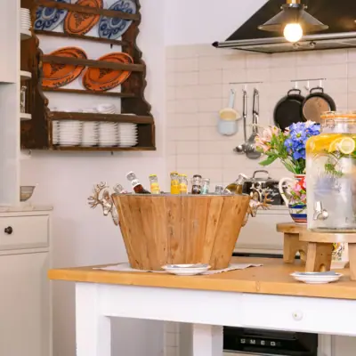 Kitchen with a wooden bucket full of bottles and flowers on the worktop
