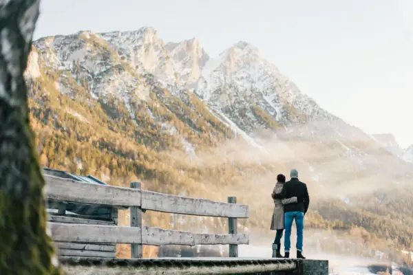 Kitzbühel Alps A man and a woman are standing on a jetty overlooking a mountain range.