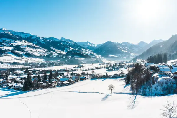 Snow-covered landscape with houses and mountains in the background.