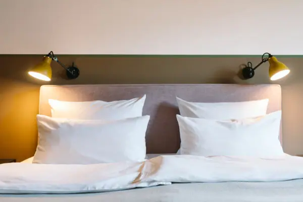 A bed with white cushions and a lamp in a hotel room at the HENRI Hotel in Garmisch-Partenkirchen.